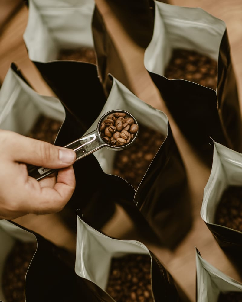 Manos empacando café en grano en bolsas